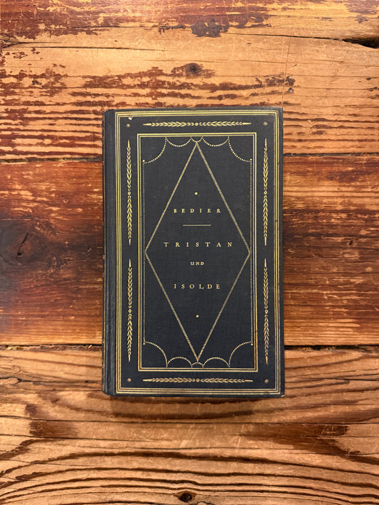 Front cover of book in German titled 'Tristan und Isolde' by Joseph Bédier, published in 1923, exposed on a wooden surfacer 
