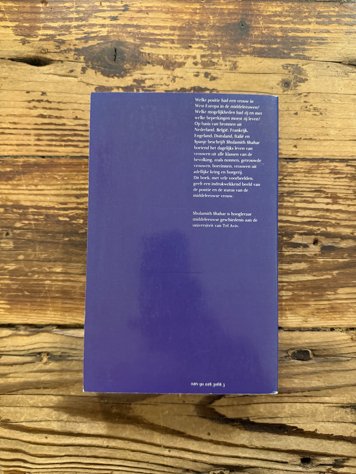 achterkant van boek met de titel 'Tussen ideaal en werkelijkheid, vrouwen in de middeleeuwse wereld' door Shulamith Shahar op een houten achtegrond 
